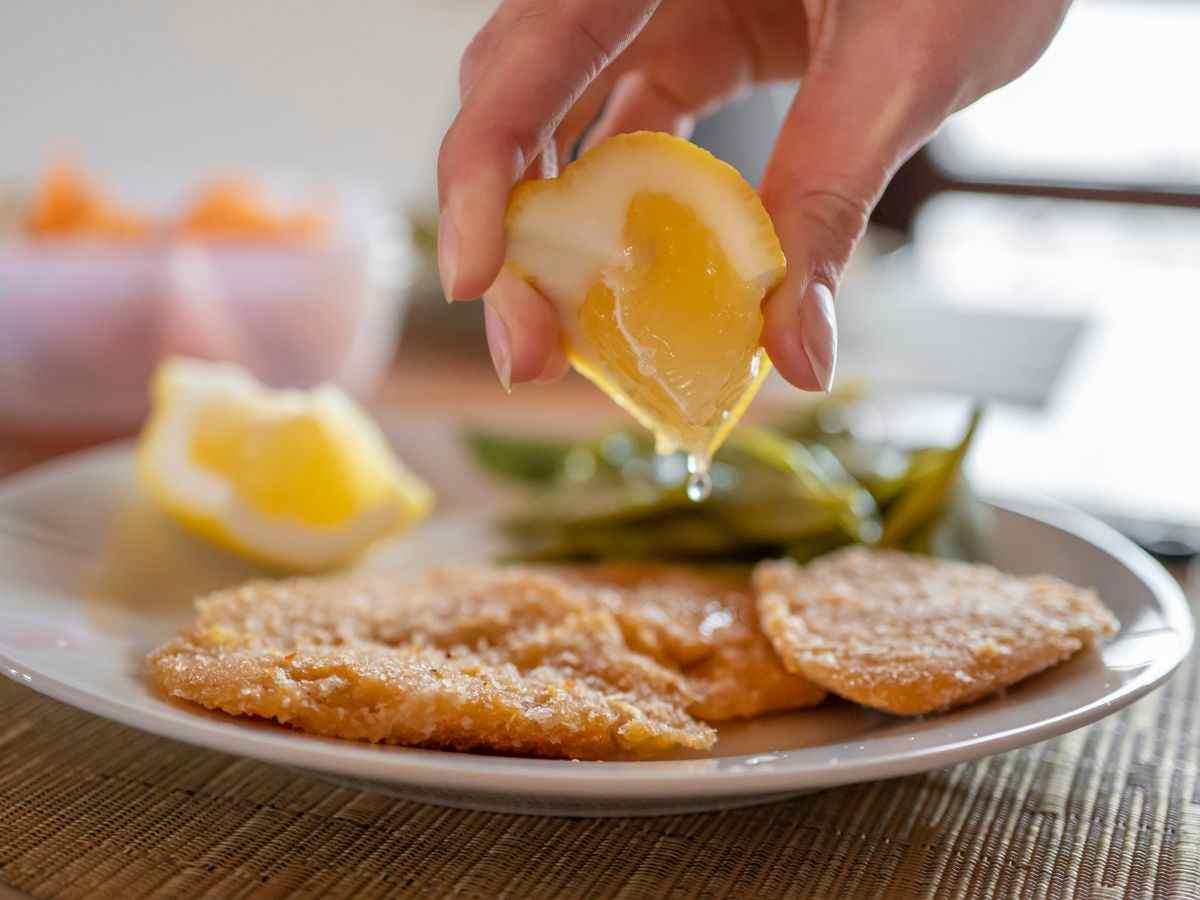 donna condisce cotolette con succo di limone